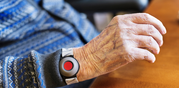 Detail image of old person's hand. Around the wrist is an alarm.