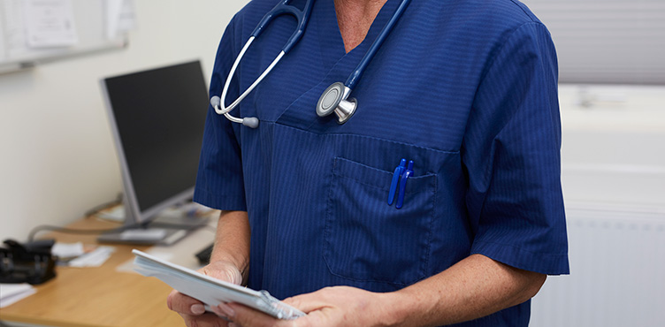 Close-up of doctor with stethoscope around the neck and a small notebook in hands.
