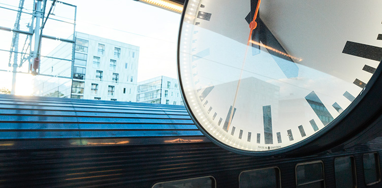 Close-up of clock at train platform. The roof of a train can be seen in the background.