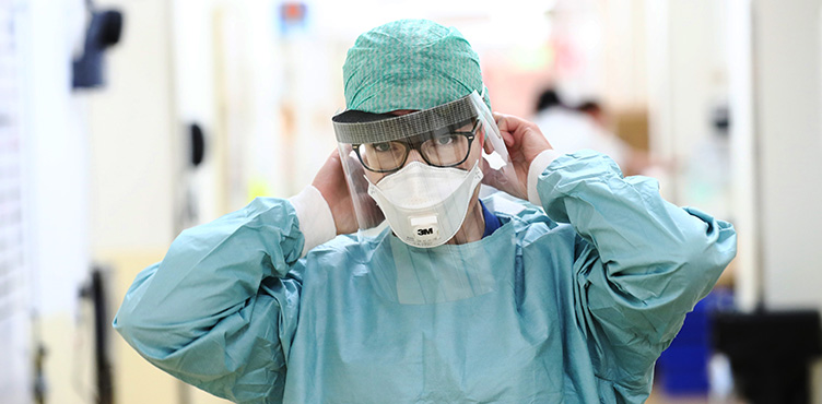 Healthcare staff adjust protective equipment, mouth guards and visors.