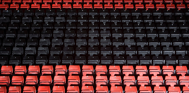 Empty grandstand with red and black plastic chairs.