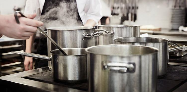 Detail image of several pans in a restaurant kitchen.