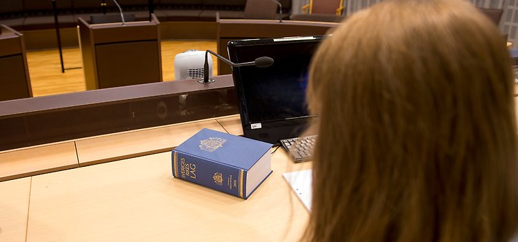 Domstolssal med lagbok och siluett av domare.
